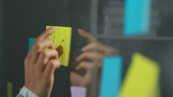 Young asian business woman working on project plan using sticky papers notes on glass wall, people meeting to share idea, Business design planning concepts. video