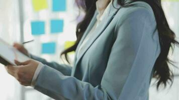 Young asian business woman working on project plan using sticky papers notes on glass wall, people meeting to share idea, Business design planning concepts. video