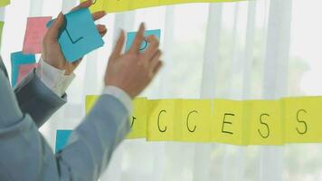 Young asian business woman working on project plan using sticky papers notes on glass wall, people meeting to share idea, Business design planning concepts. video