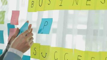 Young asian business woman working on project plan using sticky papers notes on glass wall, people meeting to share idea, Business design planning concepts. video