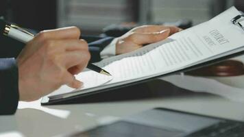 Business and lawyers discussing contract papers with brass scale on desk in office. Law, legal services, advice, justice and law concept picture with film grain effect video