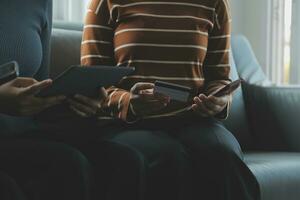 A credit card in the hands of a young businesswoman pays for a business on a mobile phone and on a desk with a laptop. photo