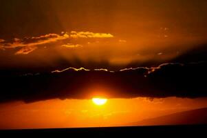 the sun is setting behind clouds in the sky photo