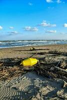 a yellow buoy sits on the beach next to a pile of debris photo