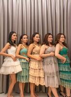 a group of Asian women are standing in front of the curtains of a luxury hotel while wearing dresses at a party photo