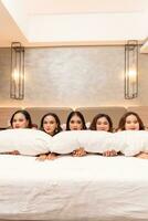 a group of Asian women are sleeping and leaning on white pillows with their friends in a luxury hotel photo