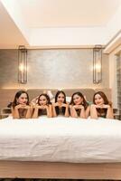 a group of Asian women are lying on white mattresses with their friends in a hotel photo