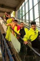 a group of Asian men in green shirts lined up on the stairs in an old building photo
