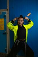 an Asian man in a green jacket posing in front of a blue locker photo