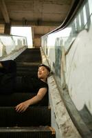 an Asian man in black clothes is sitting in a broken and abandoned elevator in an old building photo