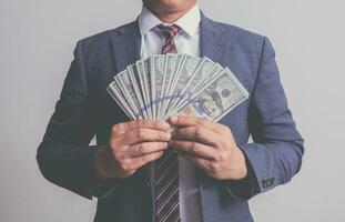 closeup businessman in suit holding one hundred 100 dollar bill. money concept photo