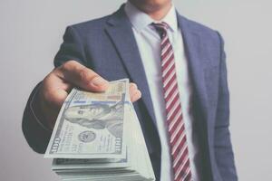 closeup businessman in suit holding one hundred 100 dollar bill. money concept photo