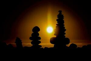 the sun is setting behind stacks of rocks photo