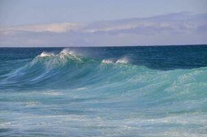 a large wave in the ocean with blue water photo