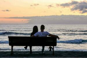 couple sitting on bench at sunset photo