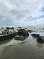 playa en un nublado día blanco arenoso playa con Roca foto