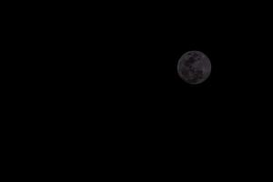 the moon is seen in the dark sky photo