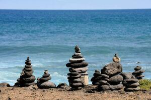 a group of rocks stacked on top of each other near the ocean photo