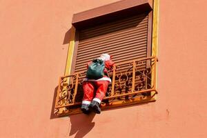 a santa claus figure hanging from a balcony photo