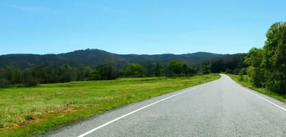 largo la carretera en el campo ambos lados de el la carretera son lleno con arboles y naturaleza largo excursiones en Días festivos foto