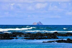 un ver de el Oceano y rocas con un pequeño isla en el distancia foto