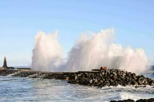 a large wave crashing into the rocks at the pier photo