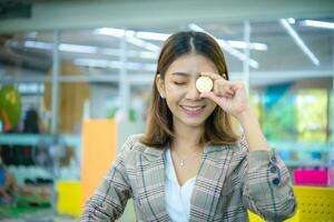 Beautiful asian business woman hold a coin in her one hand and covered on her eye  while close her eyes with a smile on her face. photo