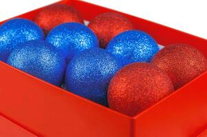 Red and blue Christmas ornament with sparkles in red packaging on a white background. photo