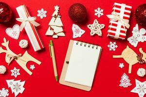 Top view of notebook on red background made of Christmas decorations. New Year time concept photo