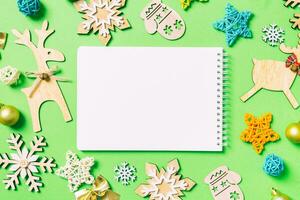 Top view of notebook on green background with New Year toys and decorations. Christmas time concept photo