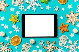 vista superior de la tableta digital sobre fondo azul con juguetes y decoraciones de año nuevo. concepto de tiempo de navidad foto