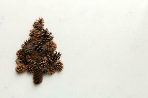 Christmas tree made from natural cones on colored background, view from above. New Year minimal concept with copy space photo