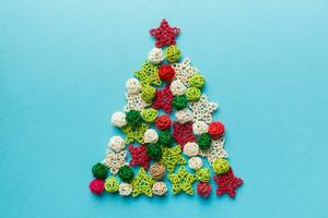 Christmas tree made from colored handmade ball decoration on colored background, view from above. New Year minimal concept with copy space photo