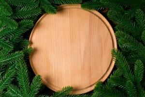 Top view of wooden plate decorated with fir tree branches. New Year dinner concept with empty space for your design photo