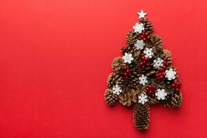 Christmas tree made from natural cones on colored background, view from above. New Year minimal concept with copy space photo