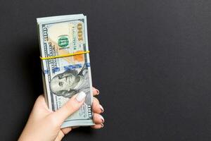 Top view of female hand holding a pack of one hundred dollar bills on colorful background. Wage and salary concept with empty space for your design photo