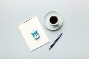 Modern office desk table with notebook and other supplies with cup of coffee. Blank notebook page for you design. Top view, flat lay photo