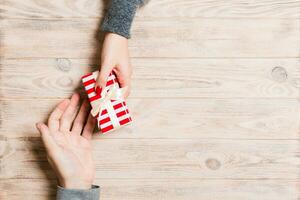 Top view of couple giving and receiving a gift on wooden background. Romantic concept with copy space photo