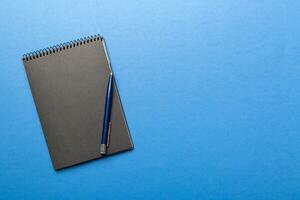 school notebook on a colored background, spiral black notepad on a table Top view photo