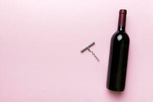 One Bottle of red wine with corkscrew on colored table. Flat lay, top view wth copy space photo