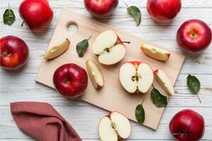 Fresh red apples with green leaves on table. cutting board with knife. Top view photo