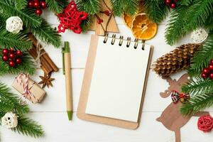 Top view of fir tree branches, notebook and festive decorative toys on wooden background. New Year time concept photo