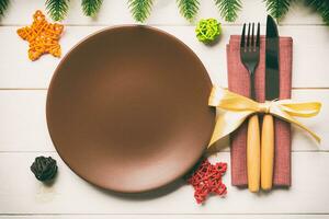 Top view of New Year dinner on festive wooden background. Composition of plate, fork, knife, fir tree and decorations. Merry Christmas concept photo