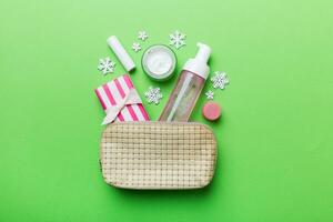 Christmas flat lay with makeup cosmetic products in cosmetic bag on colored background. Top view New year Beauty concept photo