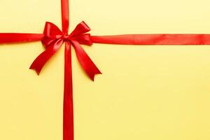 Top view of Red ribbon rolled and red bow isolated on colored background. Flat lay with copy space photo