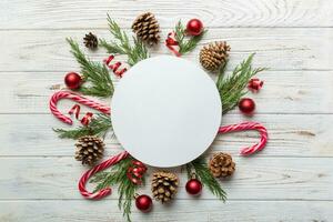 Flat lay Christmas composition. Round Paper blank, pine tree branches, christmas decorations on Colored background. Top view, copy space for text photo