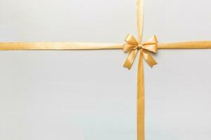 Top view of gold ribbon rolled and yellowbow isolated on colored background. Flat lay with copy space photo