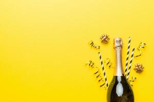 bottle of champagne with glasses and colorful confetti on colored background. top view flay lay photo