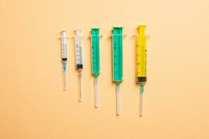 Top view of different syringes at orange background. Medical injection concept with copy space photo