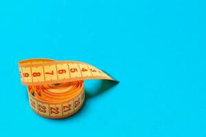 Top view of curled measuring tape as a sewing accessory on blue background. Tailor concept with copy space photo